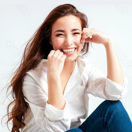 Woman smiling with brown hair wearing jeans and white blouse sitting